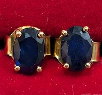 Close-up of both sapphire earrings showing prong settings and blue stones