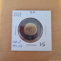 Front of coin in flip showing obverse portrait and black ring, flip labelled 2022 B.R.