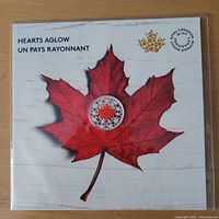 Front of sealed display card with coin centered on red maple leaf artwork