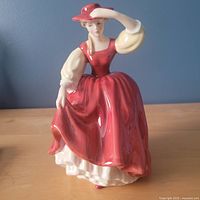 Front view of Royal Doulton Buttercup figurine showing red dress and hat