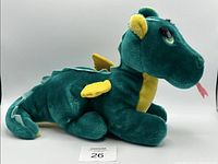 Left side profile of green and yellow Puff The Magic Dragon plush lying down