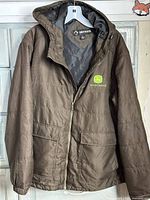 Front view of brown DRI DUCK John Deere hooded jacket