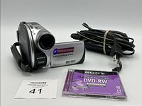 Camcorder front view with battery attached, power cable and DVD-RW disc