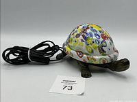 Full view of turtle lamp showing glass shell and metal body with power cord