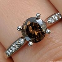 Top view of ring on finger showing brown center diamond and accent diamonds