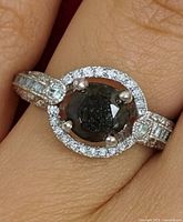 Ring on finger, showing central black diamond and halo