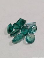 Loose emerald gemstones grouped on white surface