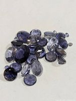 Pile of assorted faceted iolite gemstones on white background