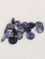 Group of loose faceted violet-blue iolite stones on white background