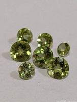Group of seven faceted peridot stones on white background
