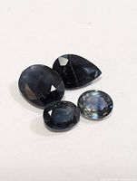 Four faceted sapphires displayed on white background