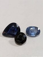 Three loose sapphires pear, oval and round cuts on white background