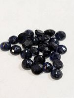 Cluster of round dark blue sapphires on white background