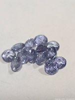 Cluster of 13 loose oval violet-blue gemstones