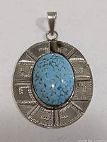 Front view of silver pendant with turquoise cabochon