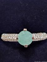 Front view showing round green CZ center and pavé band