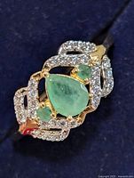 Front view of ring showing pear green stone, two small round green stones, clear CZ border