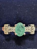 Front view of ring showing emerald and accent stones