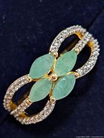 Top view of ring showing green marquise stones and CZ shoulders