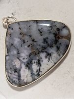 Front view of bezel-set dendritic gemstone pendant
