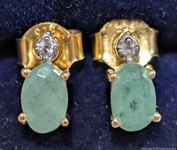 Front view of stud earrings showing emeralds and accent stones