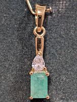 Front view of silver pendant with emerald and clear stone