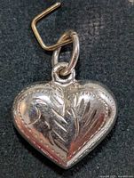 Front view of heart-shaped silver pendant showing leaf design and jump ring