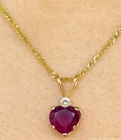 Pendant on neckline showing ruby, diamond, and gold chain