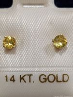 Front view of both yellow sapphire studs on card showing gold setting