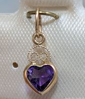 Front view showing heart amethyst set in yellow gold with scroll accent and bail