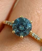 close-up of ring on finger showing blue diamond and accent stones