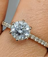 Ring on finger showing centre lab diamond and accent moissanites