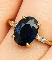 Ring on finger showing sapphire and moissanite stones