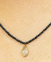 Necklace on model showing dark bead strand and clear oval diamond pendant