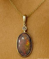 Front view showing opal, diamond accent and gold setting on chain for scale