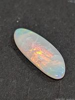 Oblique view of opal showing red and orange fire on dark background