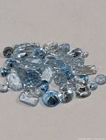 Pile of loose faceted blue topaz stones showing various cuts and colour