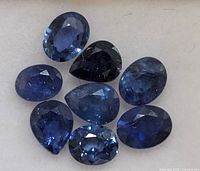 Eight loose blue sapphires on white background