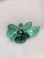 Cluster of nine loose emeralds on white background