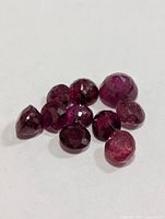 Ten loose round faceted red gemstones