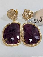 Front view of earrings showing ruby slices, pavé halo and stud