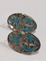Front view showing turquoise inlay and foliate engraving