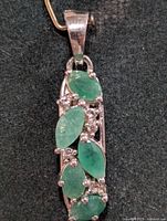 Front view of silver pendant with emerald stones
