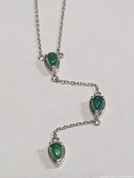 Full view of the silver necklace showing chain and three emerald drops