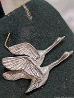Front view of silver pendant showing two swans in flight