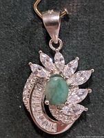 Front view of silver pendant showing green centre stone, marquise and baguette clear stones