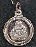 Front view of round silver Buddha pendant with beaded border and jump ring