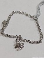 Full view of silver rolo-link bracelet with flower diamond charm