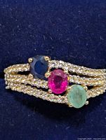 Front view of ring showing emerald, sapphire, ruby and accent stones