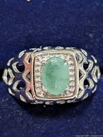 Top view of silver ring showing oval emerald, halo of accent stones, filigree shoulders